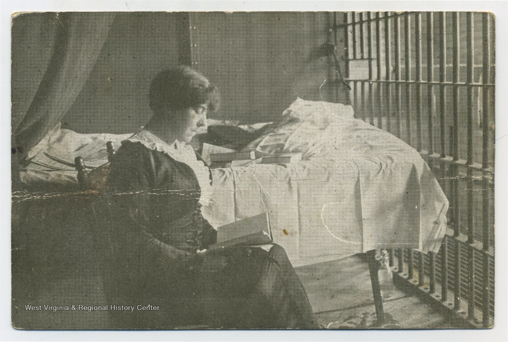 Photo postcard of Fannie Sellins, reading a book while sitting in a jail cell